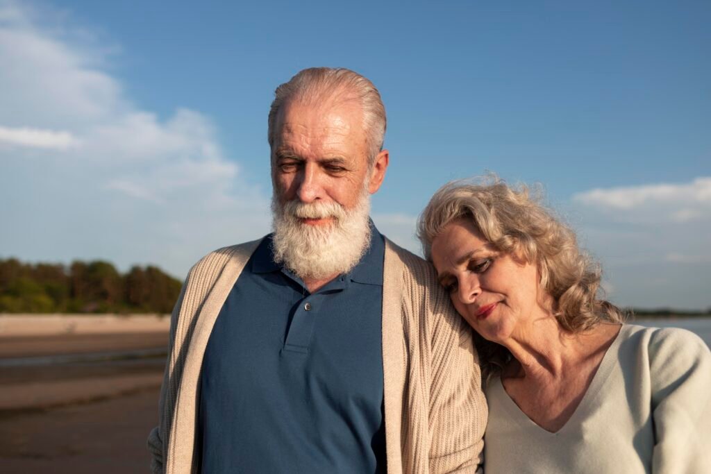 Types of love in relationships: Older couple walking outdoors by the beach, leaning on each other and showing warmth, intimacy and long-term commitment as 